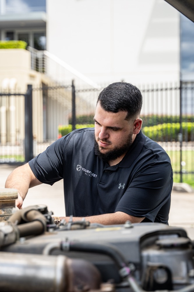 Technician checking components in a truck engine bay