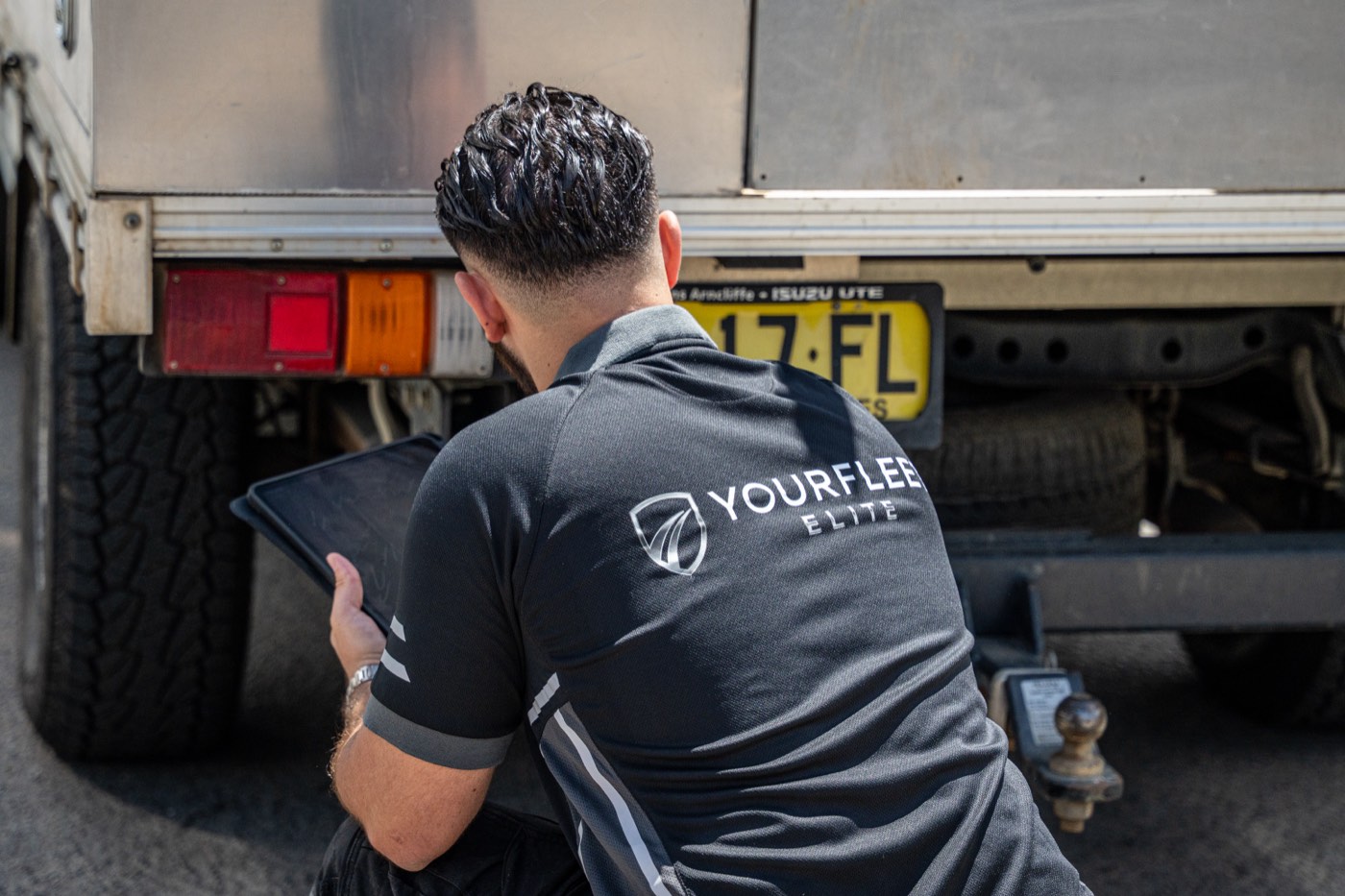 Your Fleet Elite team member logging vehicle details at the back of a ute