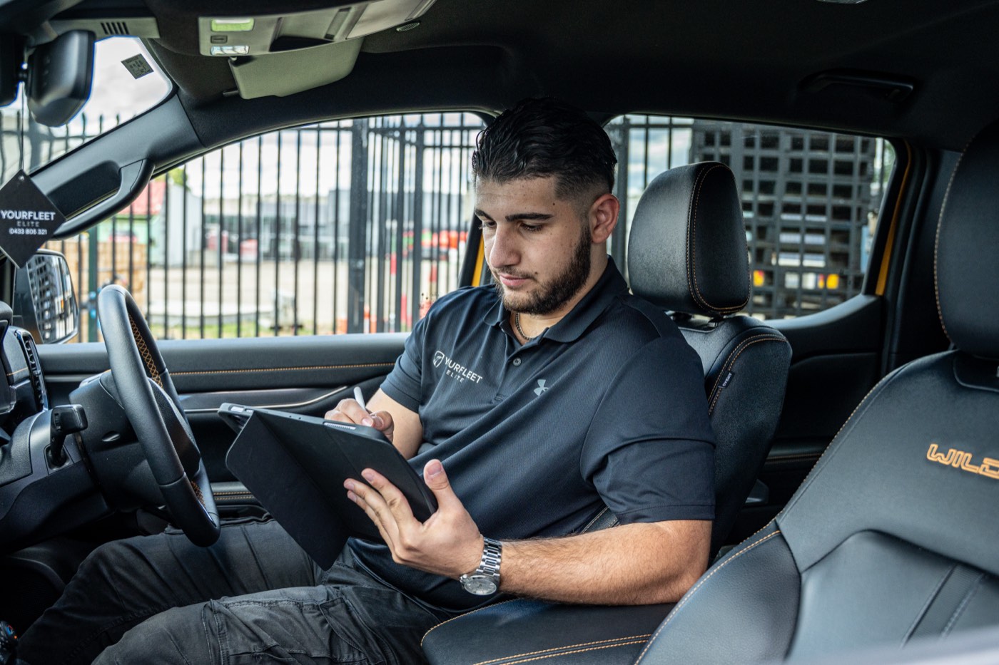 Fleet manager recording vehicle details on a tablet inside a work ute