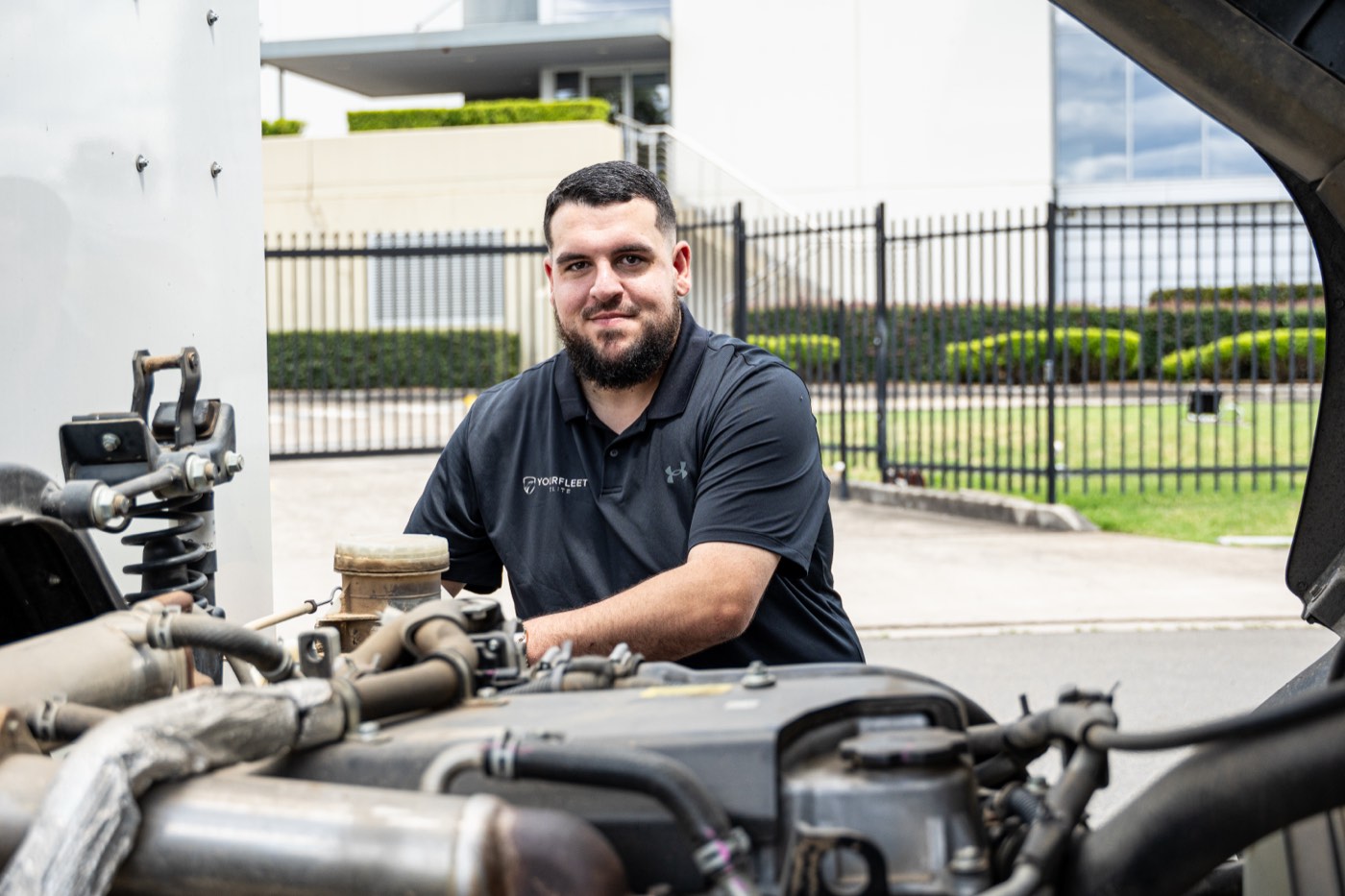 Your Fleet Elite technician smiling while working on a truck engine
